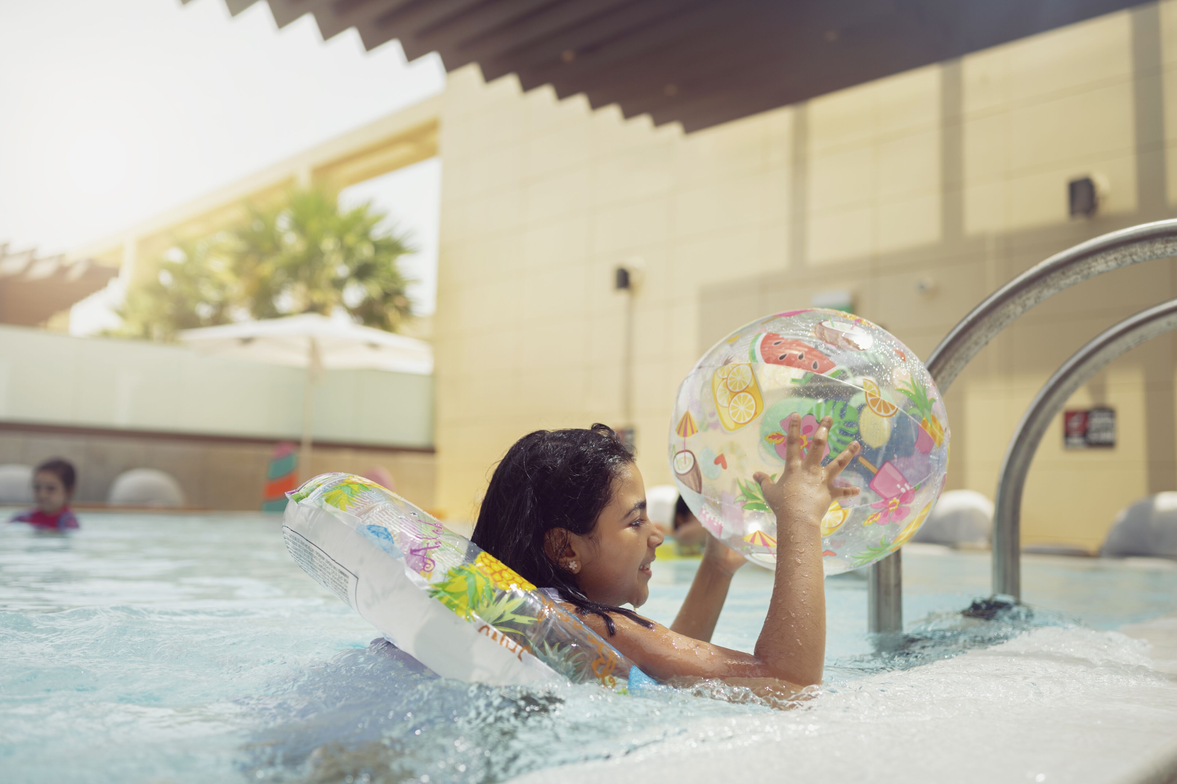A person in a swimming pool holding a colorful inflatable ball.