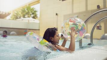 A person in a swimming pool holding a colorful inflatable ball.