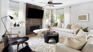 A modern living room with a fireplace, a sofa, a coffee table, and a TV mounted on the wall.