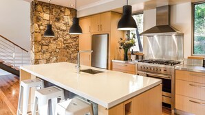 Una cocina moderna con una isla central, electrodomésticos de acero inoxidable, armarios de madera y una pared de acento de piedra.