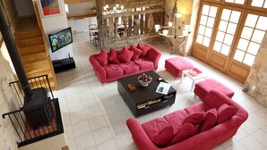 Un salón espacioso con dos sofás rojos, una mesa de centro negra y un televisor montado en la pared.