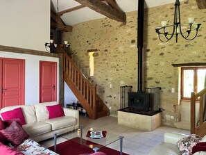 A living room with a stone wall, a fireplace, a staircase, and a sofa.