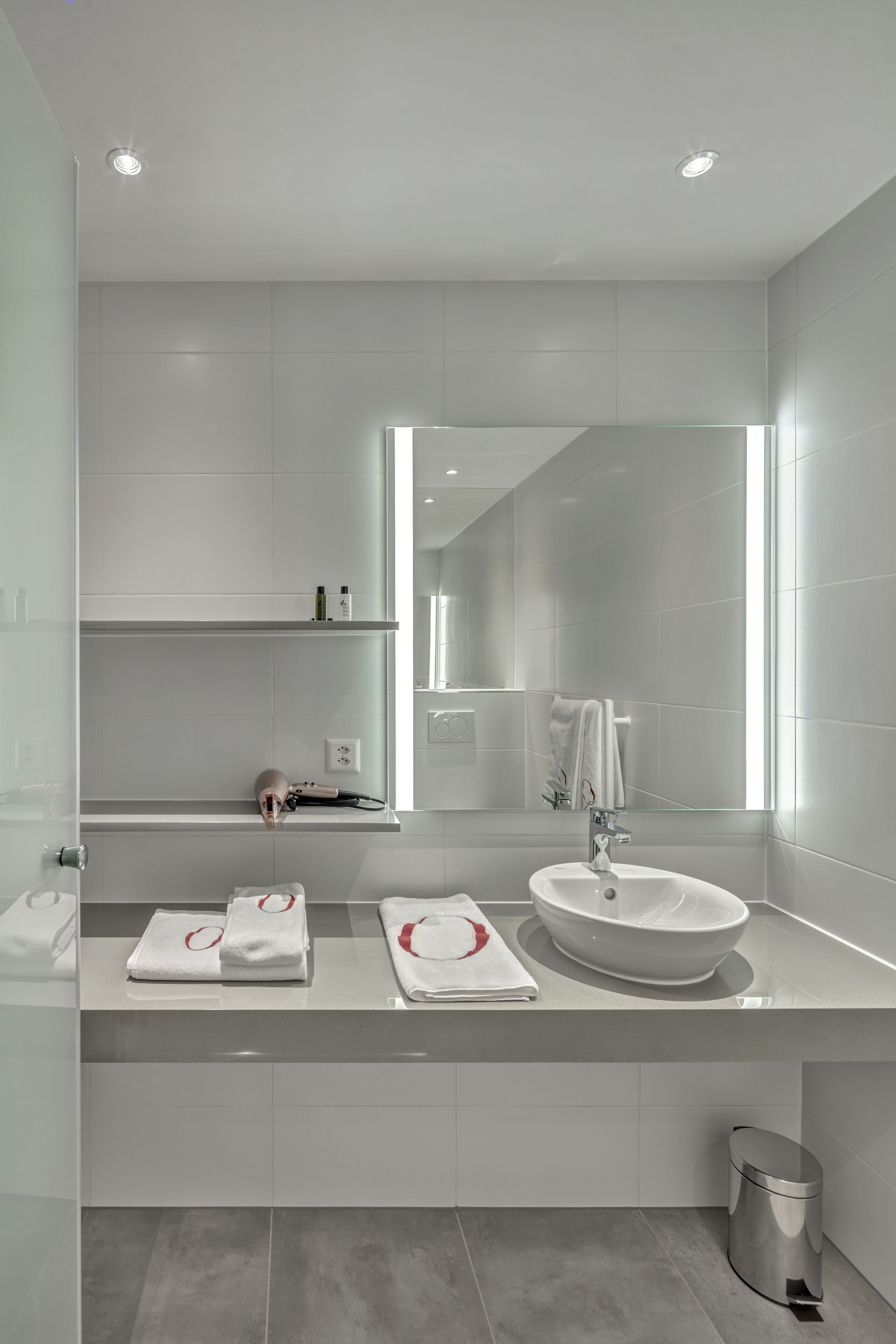 A modern bathroom with a white sink, mirror, and two towel racks.