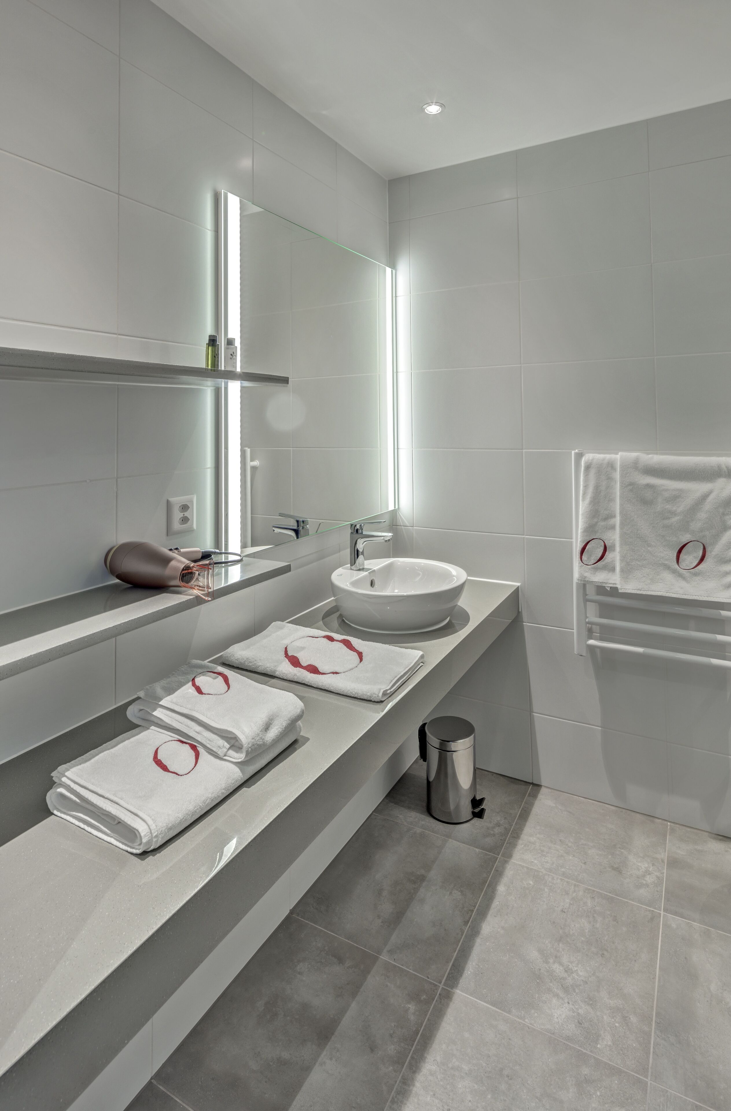 A modern bathroom with a large mirror, a sink, and a towel rack.