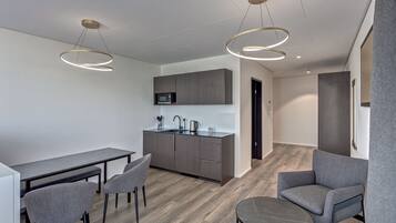 Una cocina moderna con microondas, armarios oscuros y un comedor con mesa y sillas.