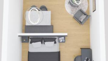 A compact hotel room with a bed, a desk, a chair, a small table, and a wardrobe.