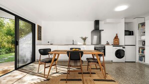 Una cocina moderna con comedor, horno empotrado y lavadora.