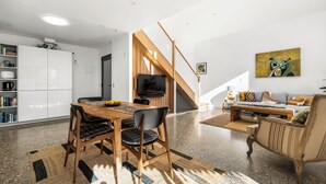 Un espacio habitable moderno con comedor, escalera y zona de estar.