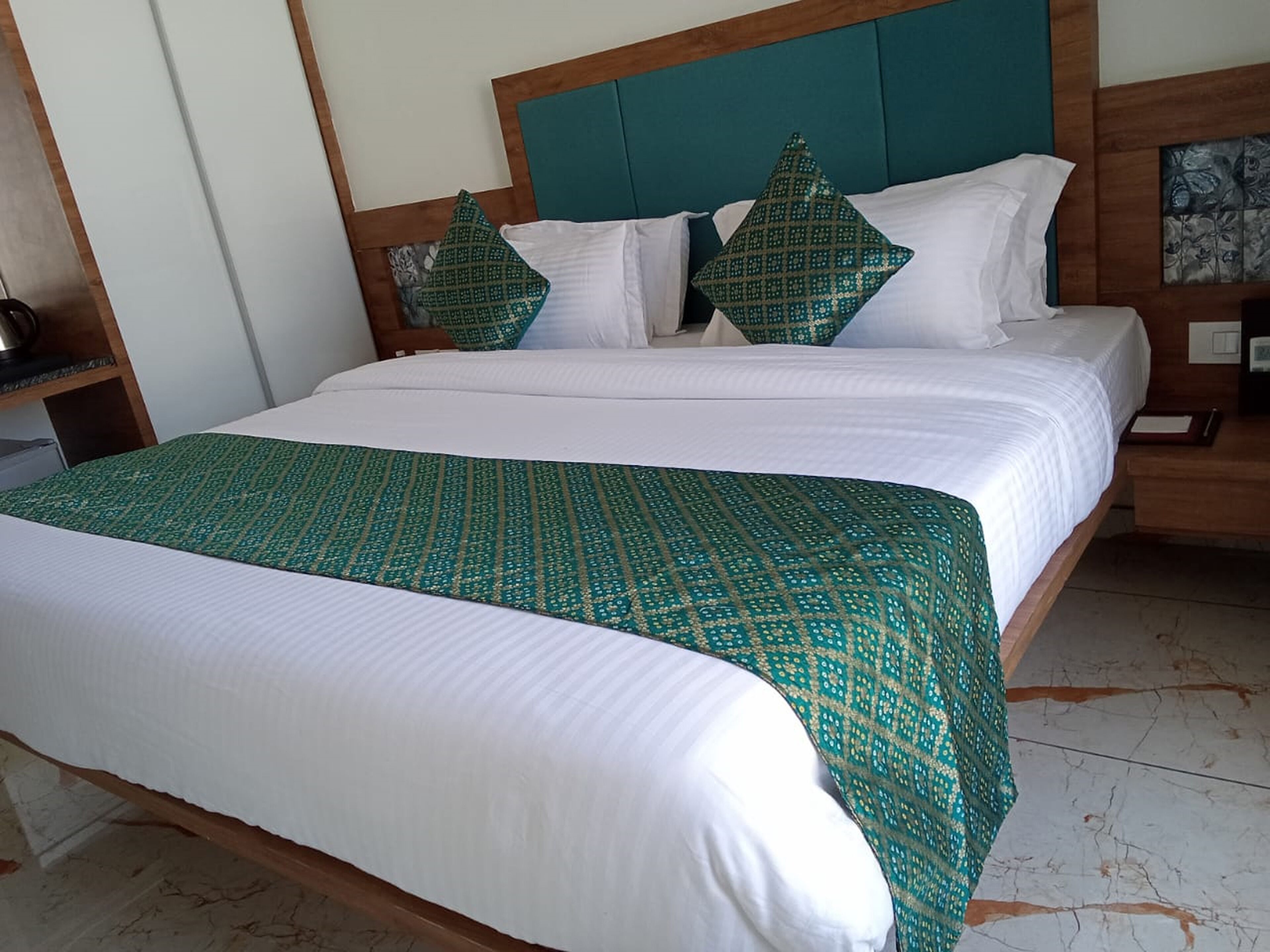 A hotel room with a bed, a nightstand, and a wooden headboard.