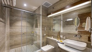 Un bagno moderno con cabina doccia in vetro, vaso sospeso e un ampio lavandino con specchio.