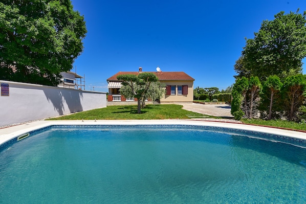 Una piscina con una casa al fondo.