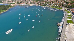 Une vue aérienne d’une marina où sont amarrés de nombreux bateaux, entourée d’un quartier résidentiel avec des maisons et de la verdure.