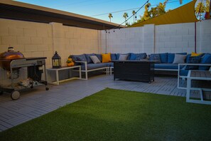 An outdoor patio with a barbecue grill, a sofa set, and a small table.