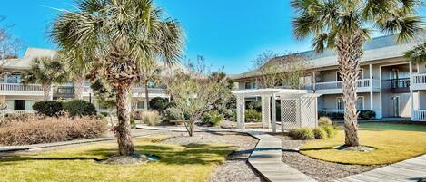 A resort with multiple-story buildings, palm trees, and a wooden boardwalk.
