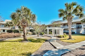 A resort with multiple-story buildings, palm trees, and a wooden walkway.