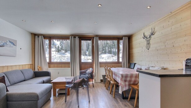 A modern interior with a wooden dining area, a sofa, and a kitchen counter.