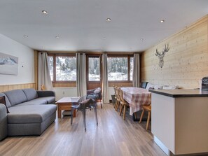 Ein modernes Interieur mit einer Essecke aus Holz, einer Couch und einer Küchenzeile.