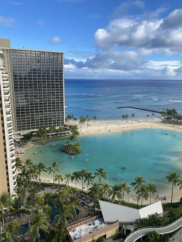 A hotel with a beach view, a pool area, and a large building with many windows. - Entire Condominium - Newly upgraded Waikiki TOP Floor ILIKAI Hotel (Honolulu)