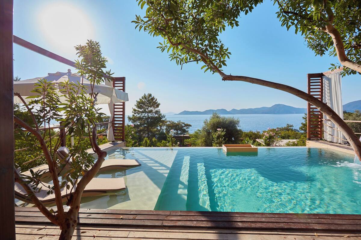 Une piscine à débordement offrant une vue imprenable sur la mer et les montagnes en arrière-plan.