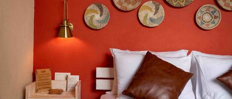 A neatly arranged hotel room with a bed, pillows, a bedside table with a lamp, and decorative plates on the wall.