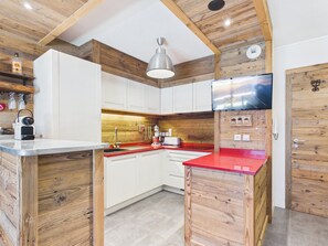 Eine moderne KĂŒche mit Holzelementen, einer roten Arbeitsplatte und einem integrierten Fernseher.