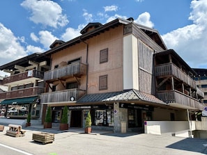 A multi-story building with wooden balconies, a ground-level shop, and a sign for 'Nicolas Thibon Immobilier.'
