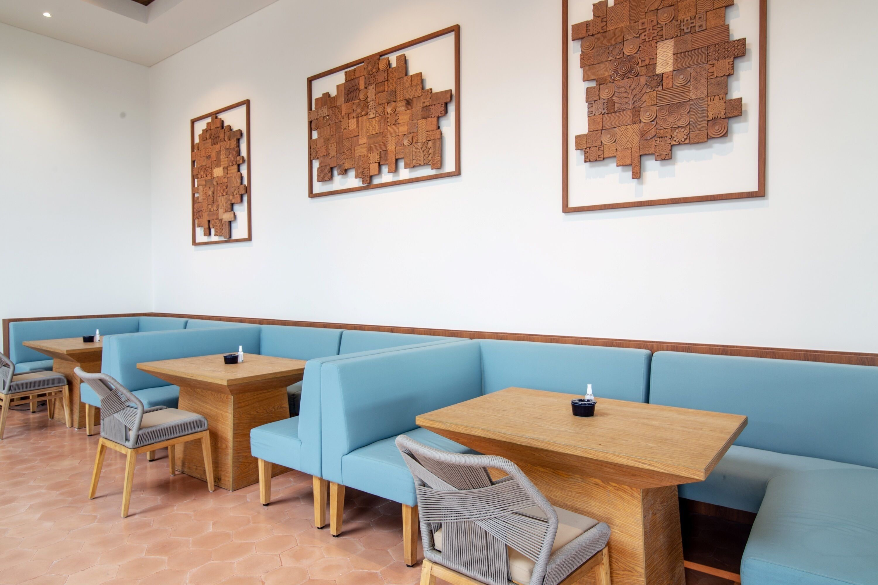 A restaurant with blue cushioned booths and wooden tables, featuring wall-mounted wooden art pieces.