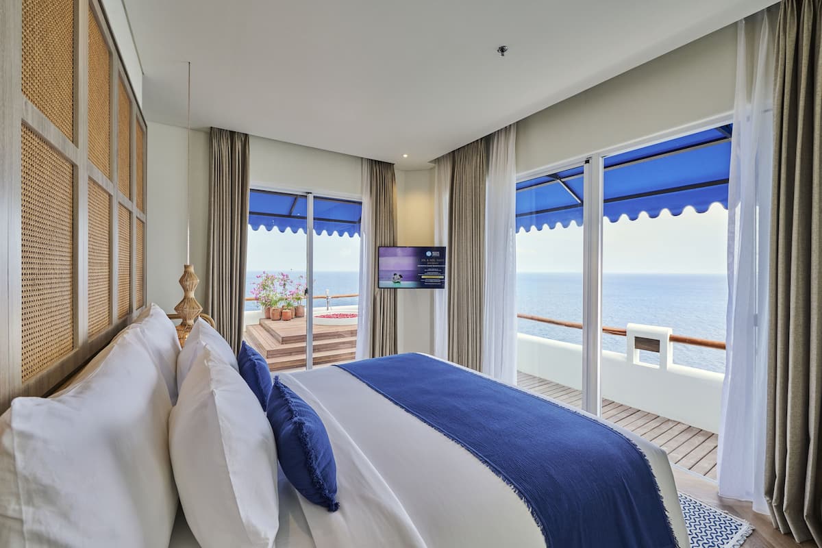 Une chambre dotée d’un grand lit, d’une télévision et d’un balcon offrant une vue sur la mer.