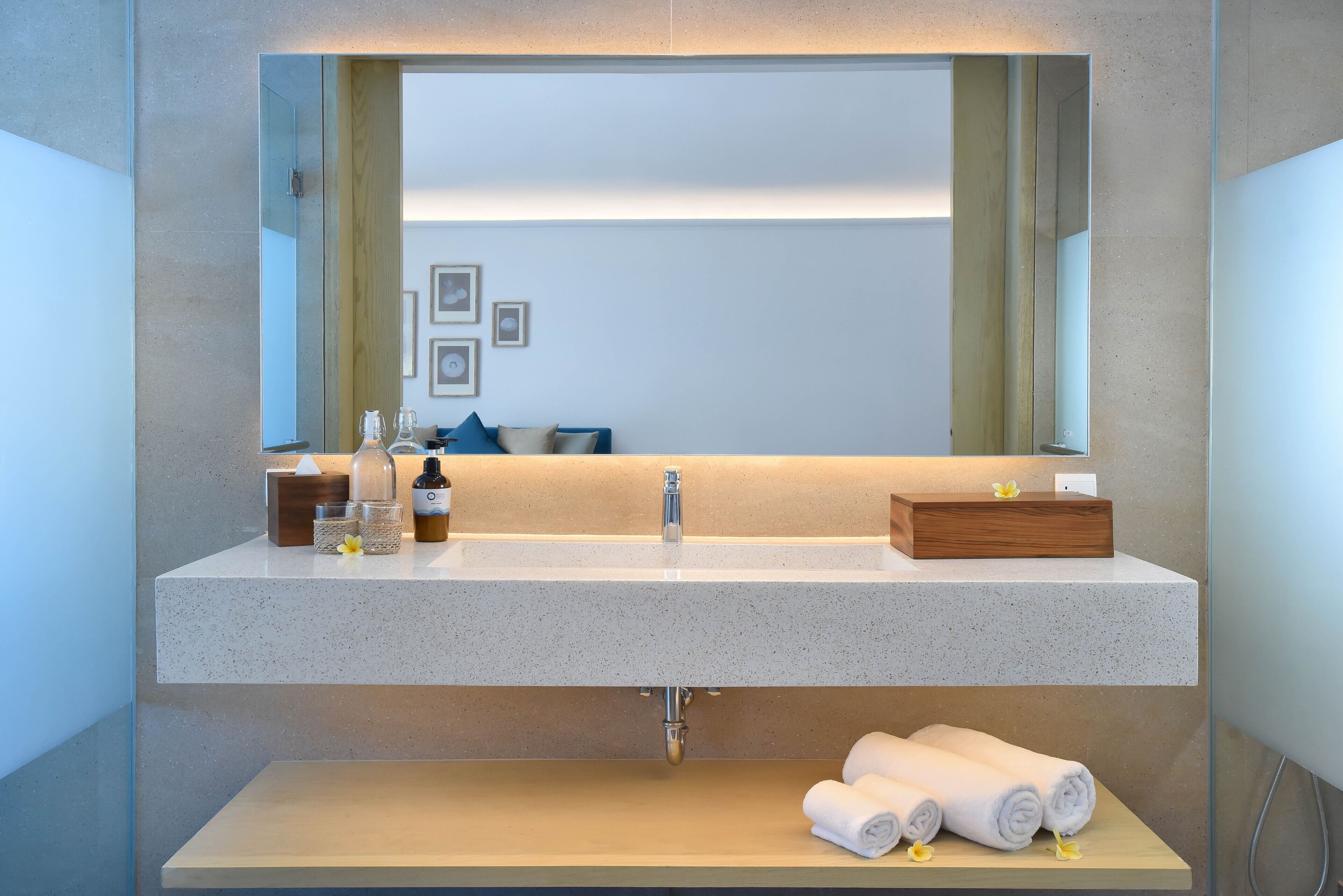 Une salle de bain moderne avec un grand miroir, un lavabo et une étagère en bois en dessous.