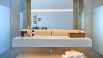 Une salle de bain moderne avec un grand miroir, un lavabo et une étagère en bois en dessous.