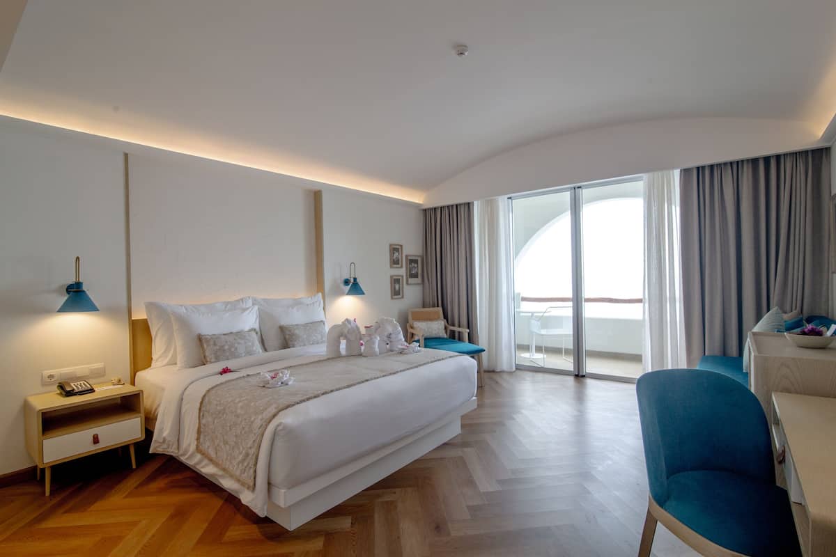 Une chambre d’hôtel moderne dotée d’un grand lit, d’un bureau et d’un balcon avec des rideaux.