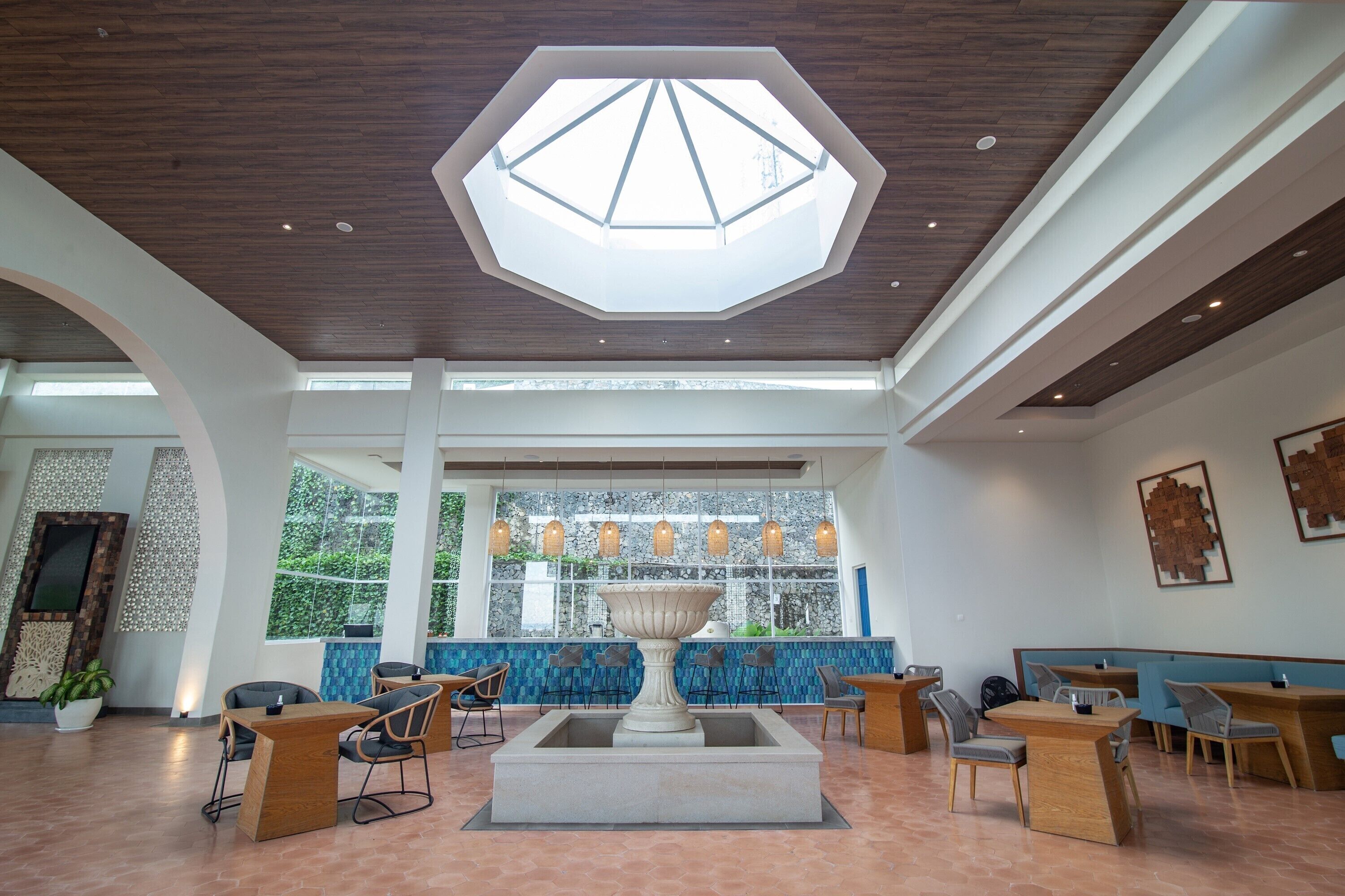 A spacious lobby with a central fountain, seating areas, and a large skylight.