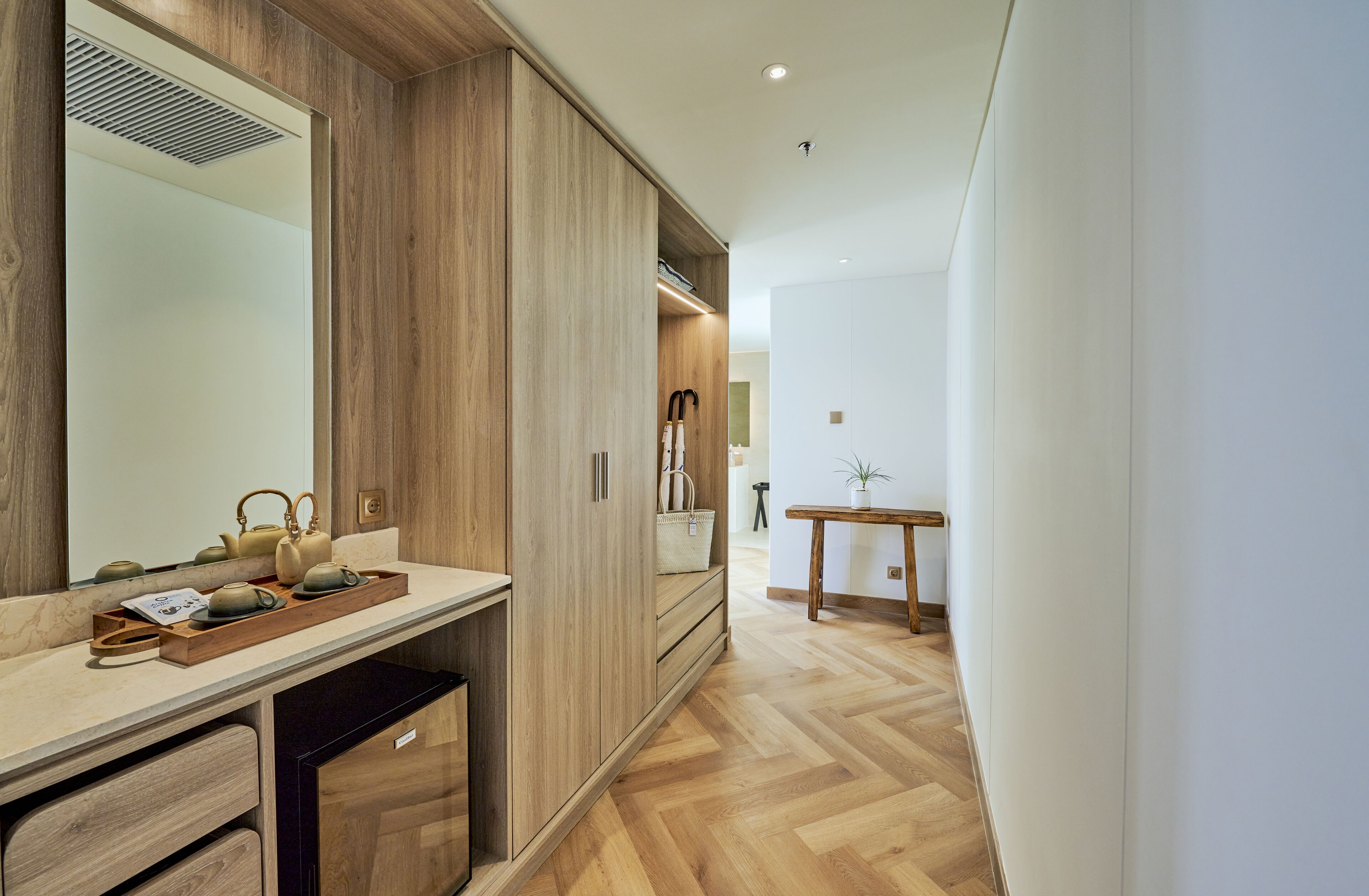 A modern bathroom with a wooden vanity, a mirror, and a wooden floor.