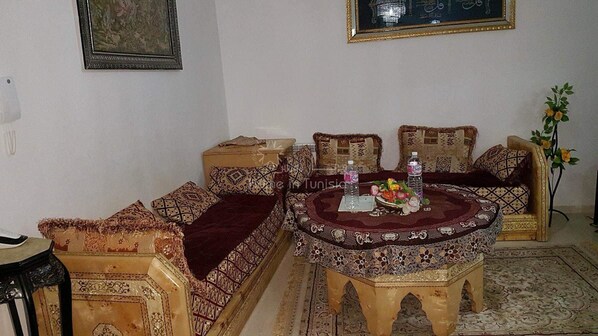 A traditional Moroccan-style living room with a sofa set, a coffee table, and a decorative rug.