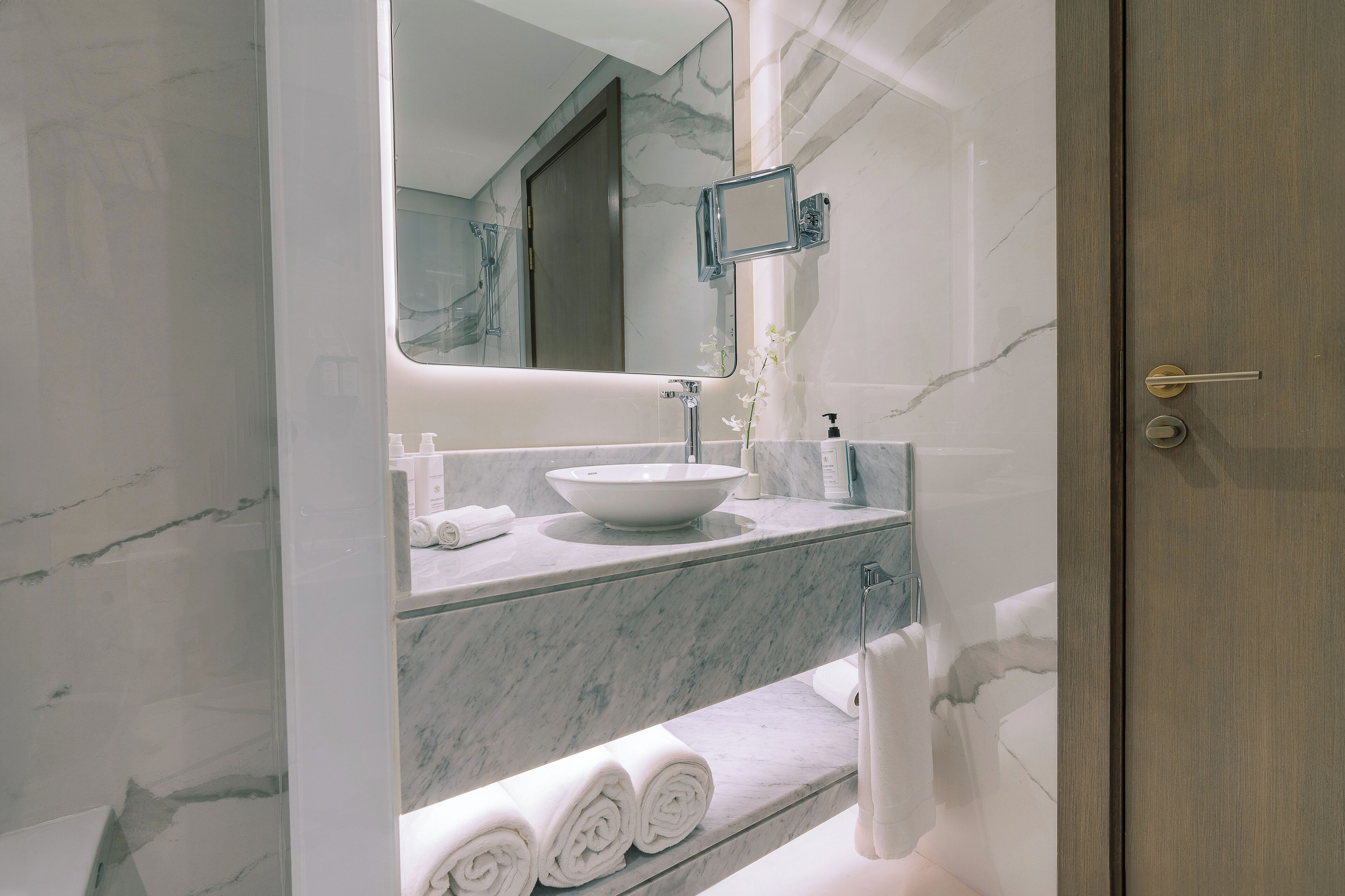 Une salle de bain avec un lavabo en marbre, un miroir et un porte-serviettes.