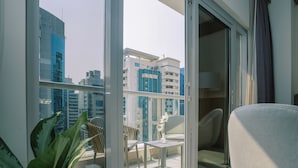 A modern balcony with a glass door, a small table with a vase of flowers, and a chair. - Khalidia Palace Hotel Dubai (Dubai)