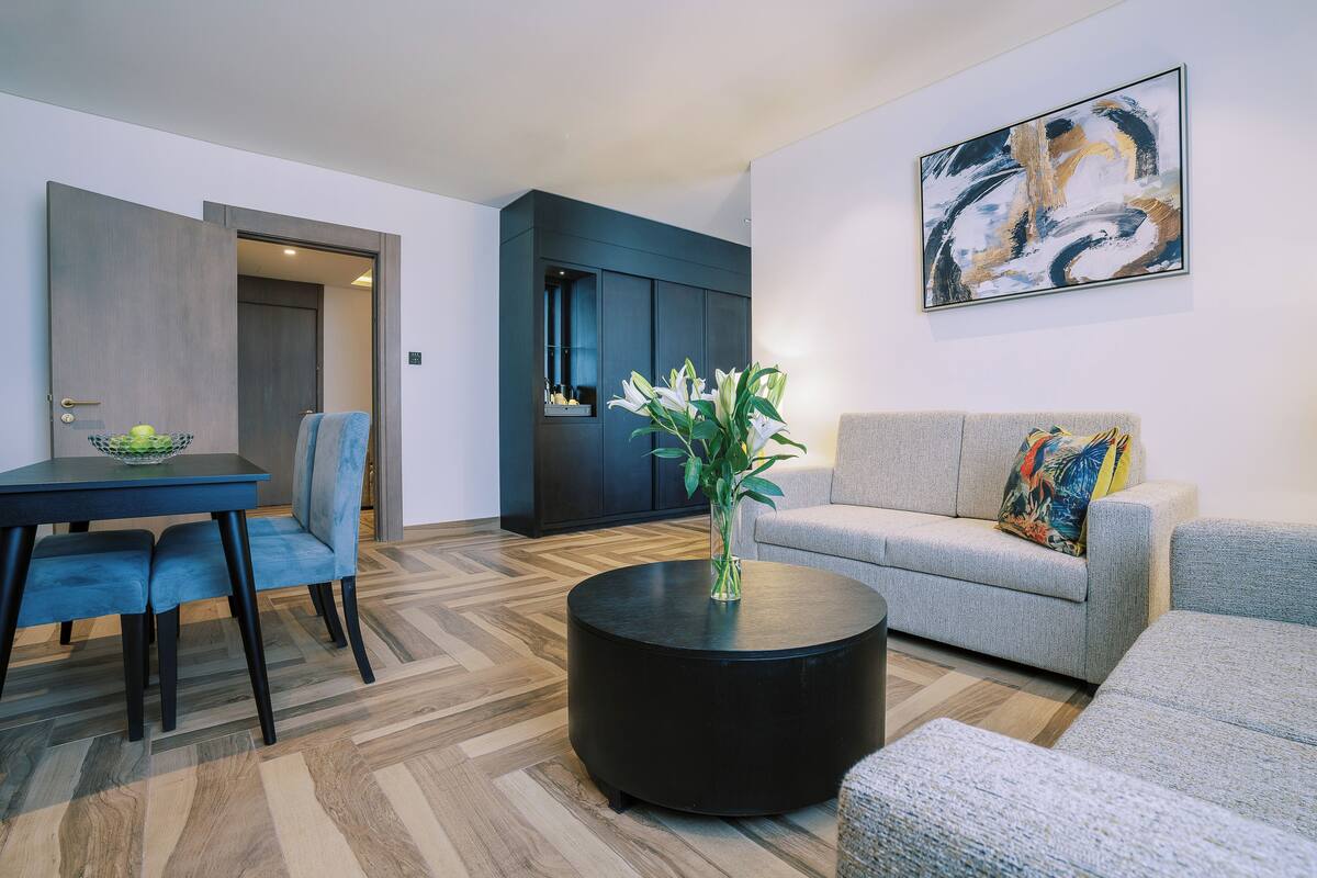 A modern living room with a sofa, a round coffee table, and a dining area with chairs and a table.
