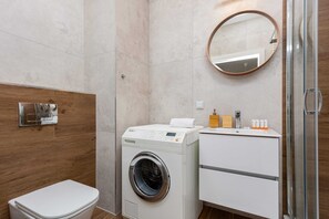 Un bagno moderno con lavatrice, servizi igienici e un mobile vanitario con specchio.