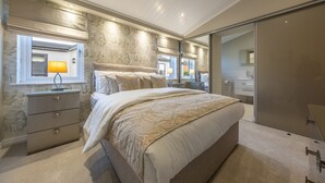 A bedroom with a large bed, bedside lamps, a dresser, and a walk-in closet. - Field Lodge, Burnham Market, Norfolk (Burnham Market)