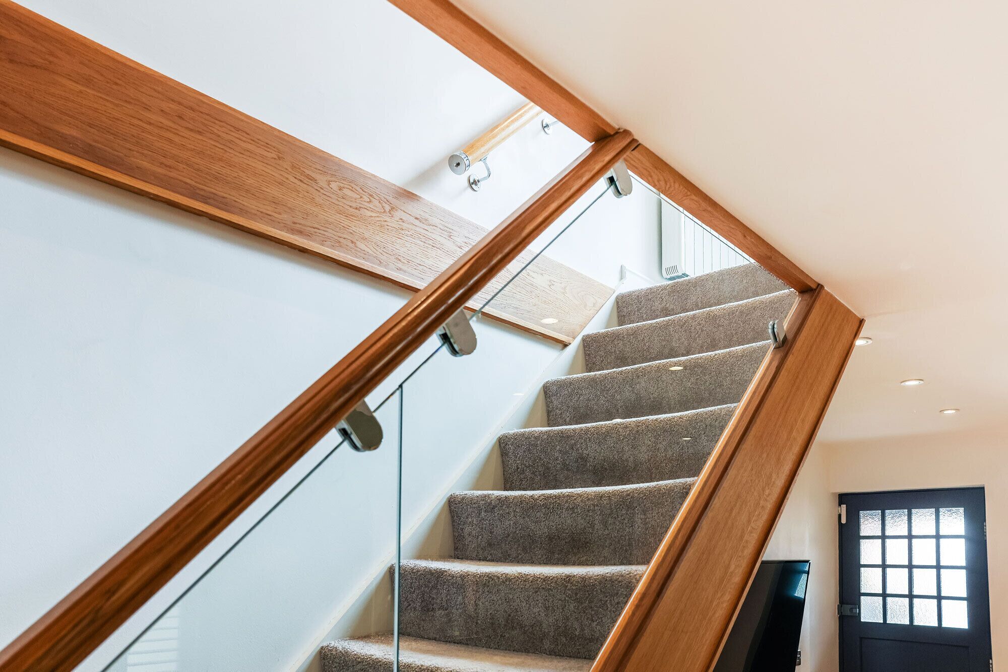 A modern staircase with glass railings and wooden steps.