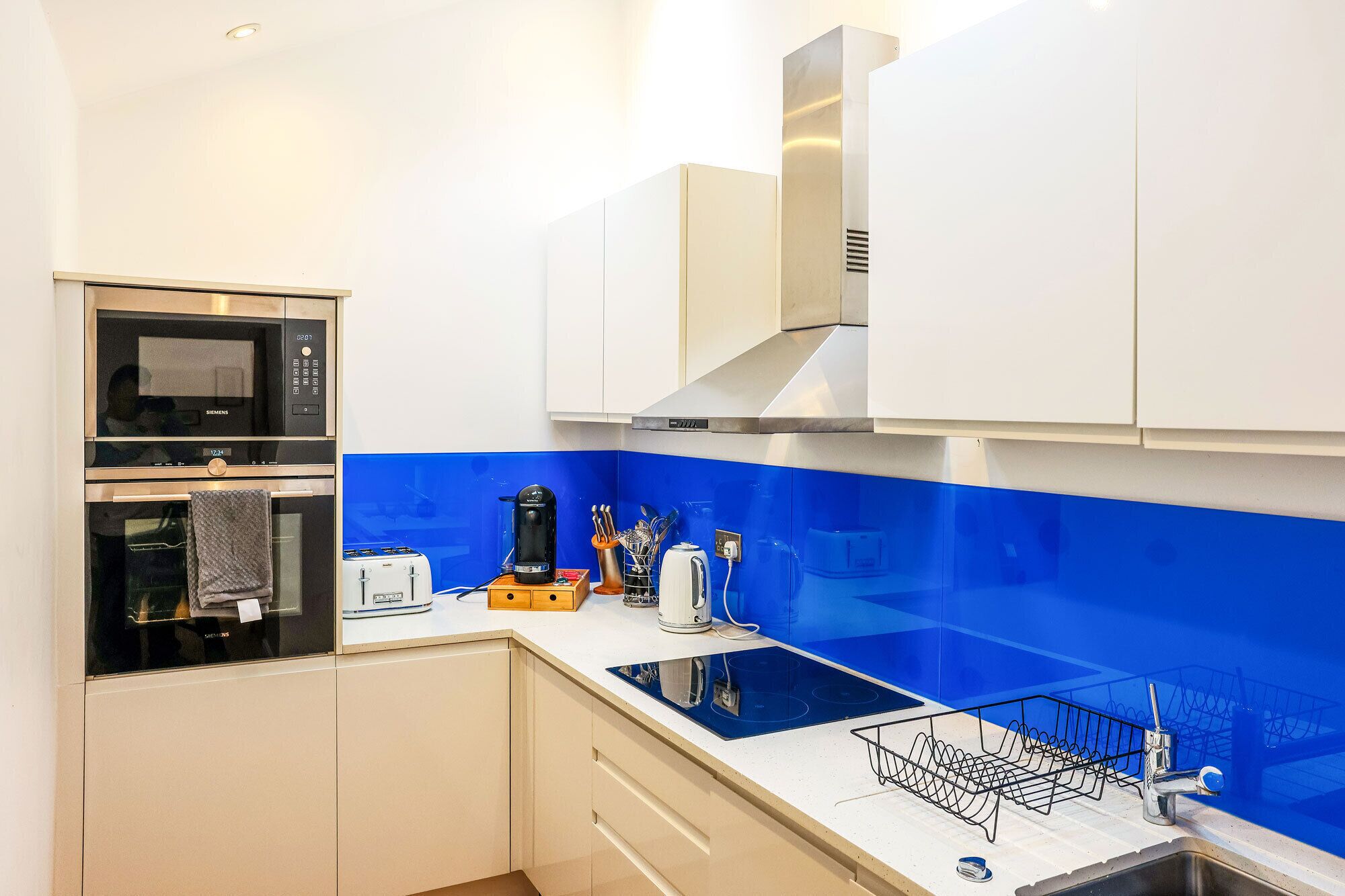 A modern kitchen with a built-in oven, microwave, and a stainless steel range hood.