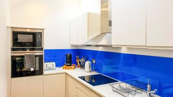 A modern kitchen with a built-in oven, microwave, and a stainless steel range hood.