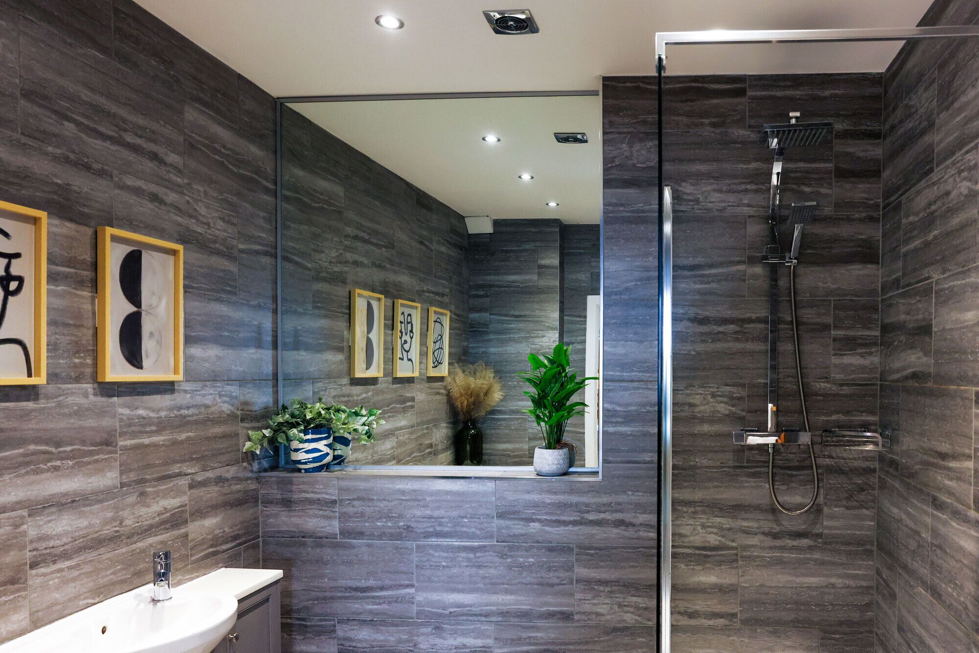 A modern bathroom with a glass shower enclosure, a sink, and decorative wall art.