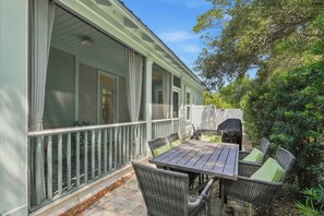 A covered patio with a table and chairs, a grill, and a white fence. - Beach cottage w/ heated pool & fenced yard (Panama City Beach)