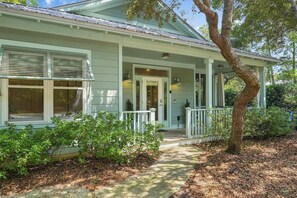 A light green house with a porch, a door, and a window.