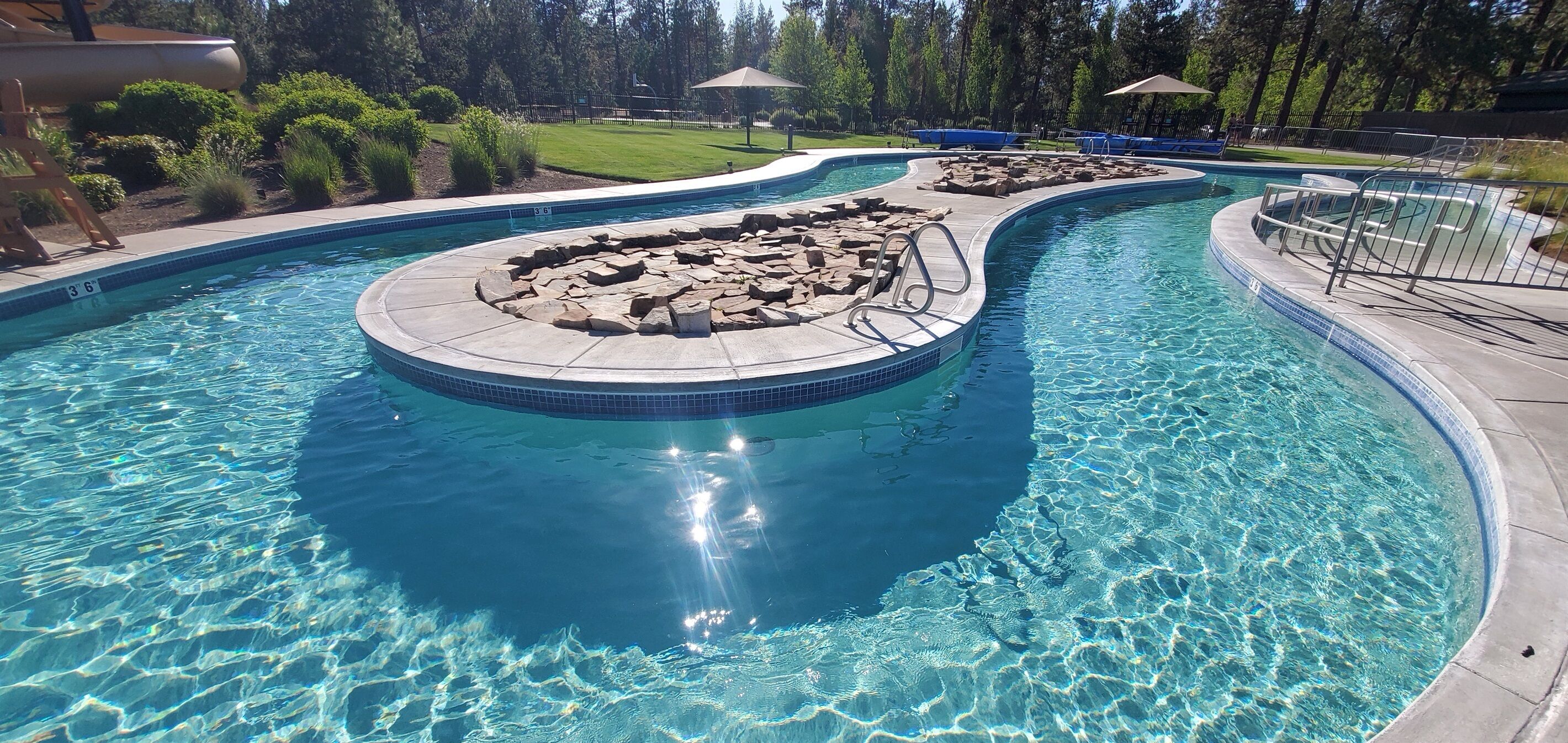 A swimming pool with a circular rock feature and a surrounding deck.