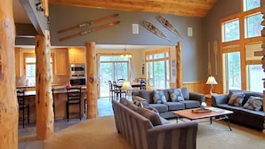 A cozy cabin interior with a dining area, a sofa, and a fireplace. - PNW Luxe Lodge- 4 Suites, Game Rm, Loft, 12xSHARC, Bikes, Hot Tub, Big Deck, ADA (Sunriver)