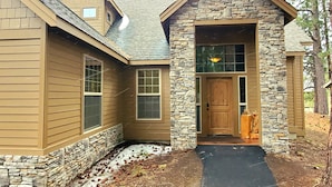 A house with a stone facade, a wooden door, and a black driveway. - PNW Luxe Lodge- 4 Suites, Game Rm, Loft, 12xSHARC, Bikes, Hot Tub, Big Deck, ADA (Sunriver)