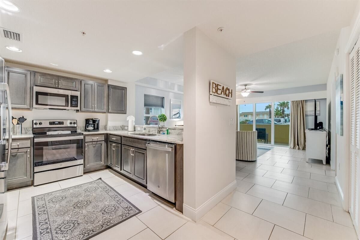 A modern kitchen with stainless steel appliances, a large island, and a view to the outside.