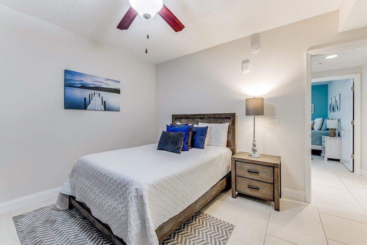 A bedroom with a bed, nightstand, and a painting on the wall.